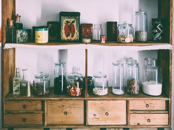 Pantry items on wooden shelves by Sándor Bányai on Unsplash.