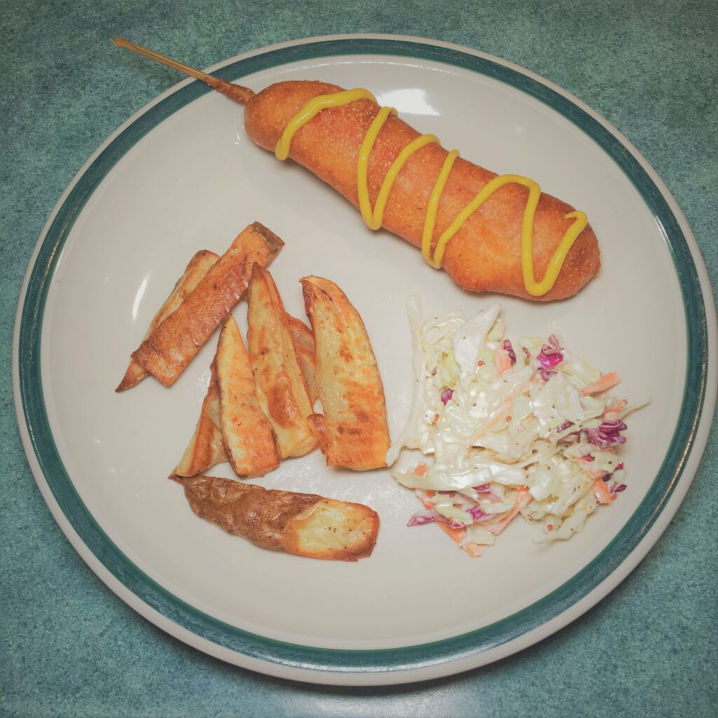 Corn dog, coleslaw, and potato wedges. 