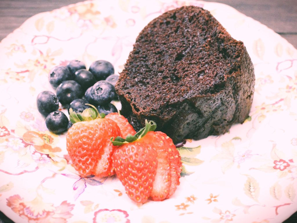 Chocolate cake on a floral plate with strawberries and blueberries by Crystal Smith.