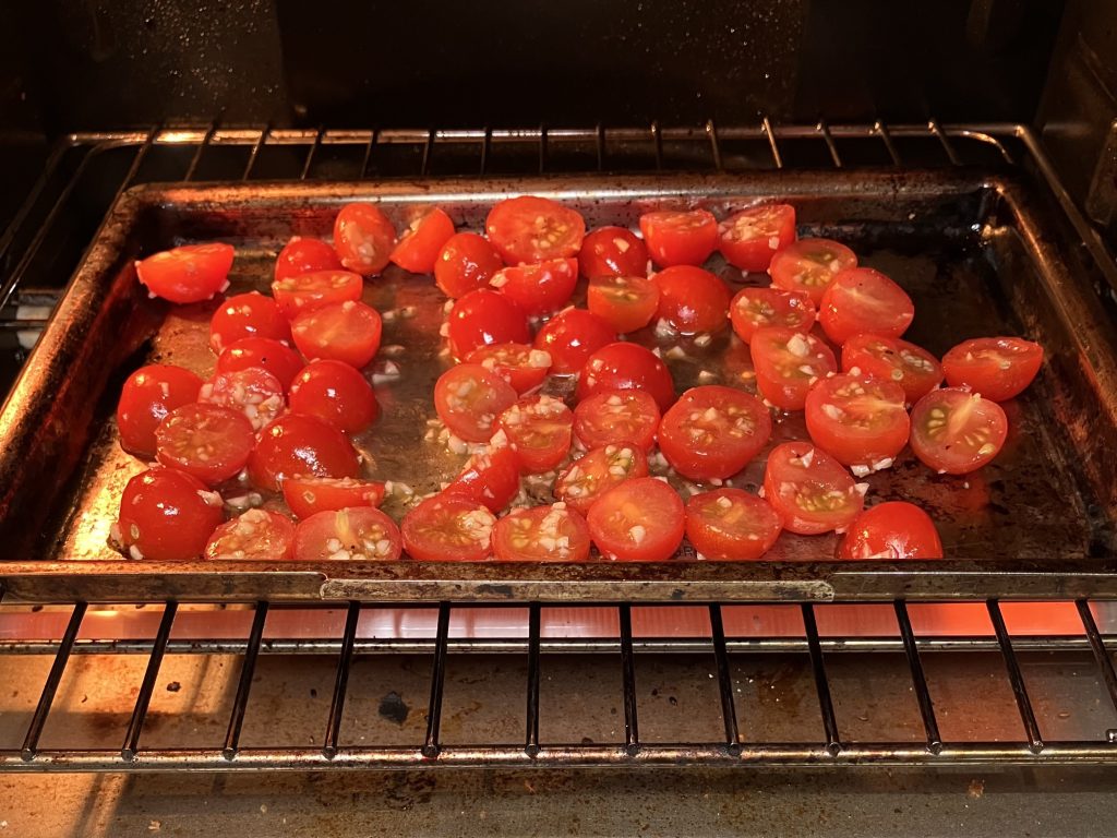 Cherry tomatoes roasting in an oven.