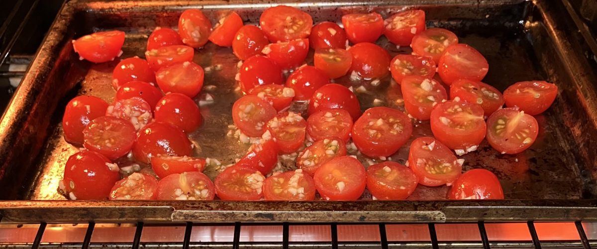 Cherry tomatoes roasting in an oven.