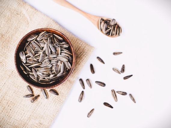 Sunflower seeds in a bowl on burlap with some scattered beside by Zulfahmi Al Ridhawi on Unsplash.